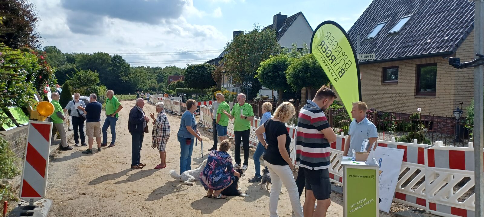 BfB-Mitglieder im Gespräch mit Bürgerinnen und Bürgern an einer Baustelle in Schenefeld, daneben ein BfB-Beachflag.